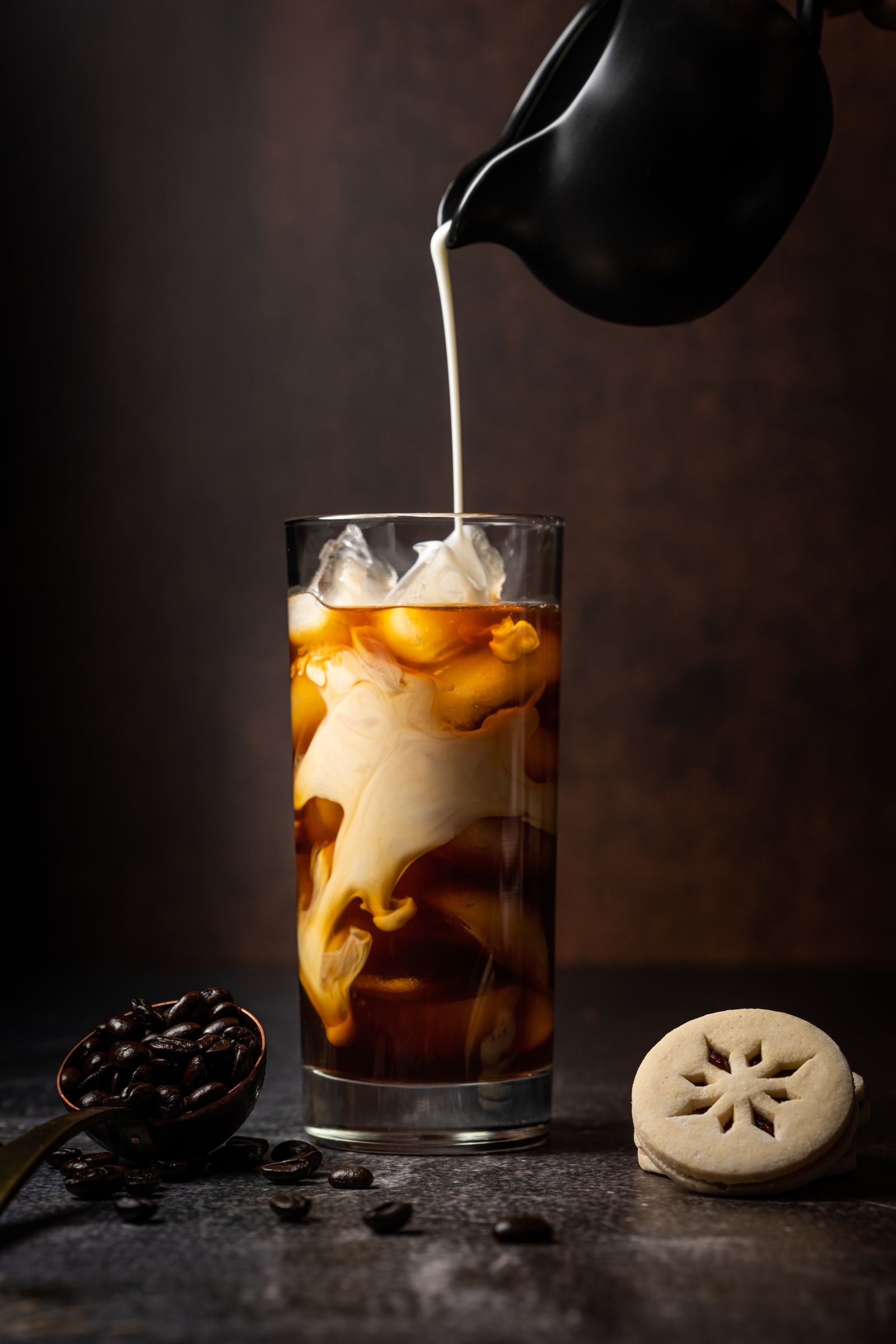 Milk being poured into a tall glass of dark iced coffee (placeholder — awaiting client photos)